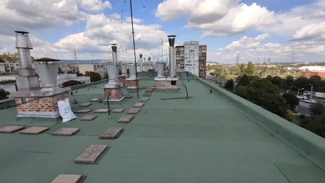 Zöld bitumenes tető téglaalapú szellőzőkkel és szétszórt járólapokkal