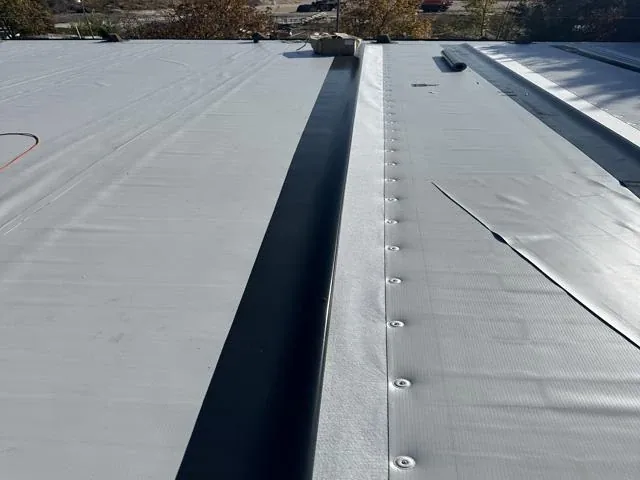 PVC lemez varratának és rögzítőcsavarjainak közeli képe sötét sáv mellett