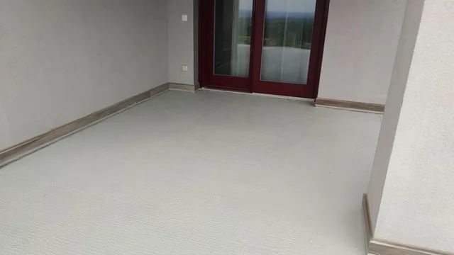 Üres, texturált szürke teraszpadló bordó keretes ajtók és sarokfal előtt