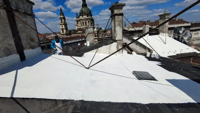 Fehér szigetelésű tető munkatárssal, kéményekkel és kupolás épülettel a háttérben